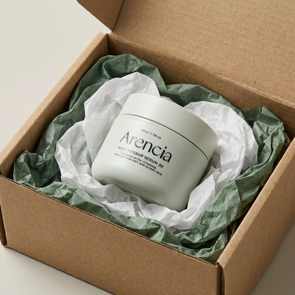 Angle : Vue oblique à mi-hauteur.  Scène : Le pot d'Arencia de l'image image_c21e9d.jpg est fermé avec son couvercle. Il est présenté à l'intérieur d'un coffret de livraison e-commerce en carton kraft brut ouvert. Le produit est niché au milieu d'une superposition de papiers de soie froissés de deux couleurs : l'un blanc laiteux, l'autre vert sauge foncé pour rappeler la couleur du sérum.  Fond & Lumière : Surface de studio mate et contemporaine. Éclairage uniforme et lumineux, valorisant l'engagement natur