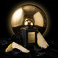 Un plan moyen d'un flacon de parfum noir mat image_2.png posé sur une surface de velours noir profond. Derrière lui, un grand disque sphérique en or poli imite une éclipse, reflétant une lumière tamisée. Le capuchon sphérique doré de image_2.png est parfaitement aligné avec l'éclipse. Autour du flacon, quelques pétales de rose noire et des quartiers de poire William fraîche sont délicatement posés. Style : Photographie d'art conceptuelle, hyper-détaillée. (gemini-3-pro-image-preview)