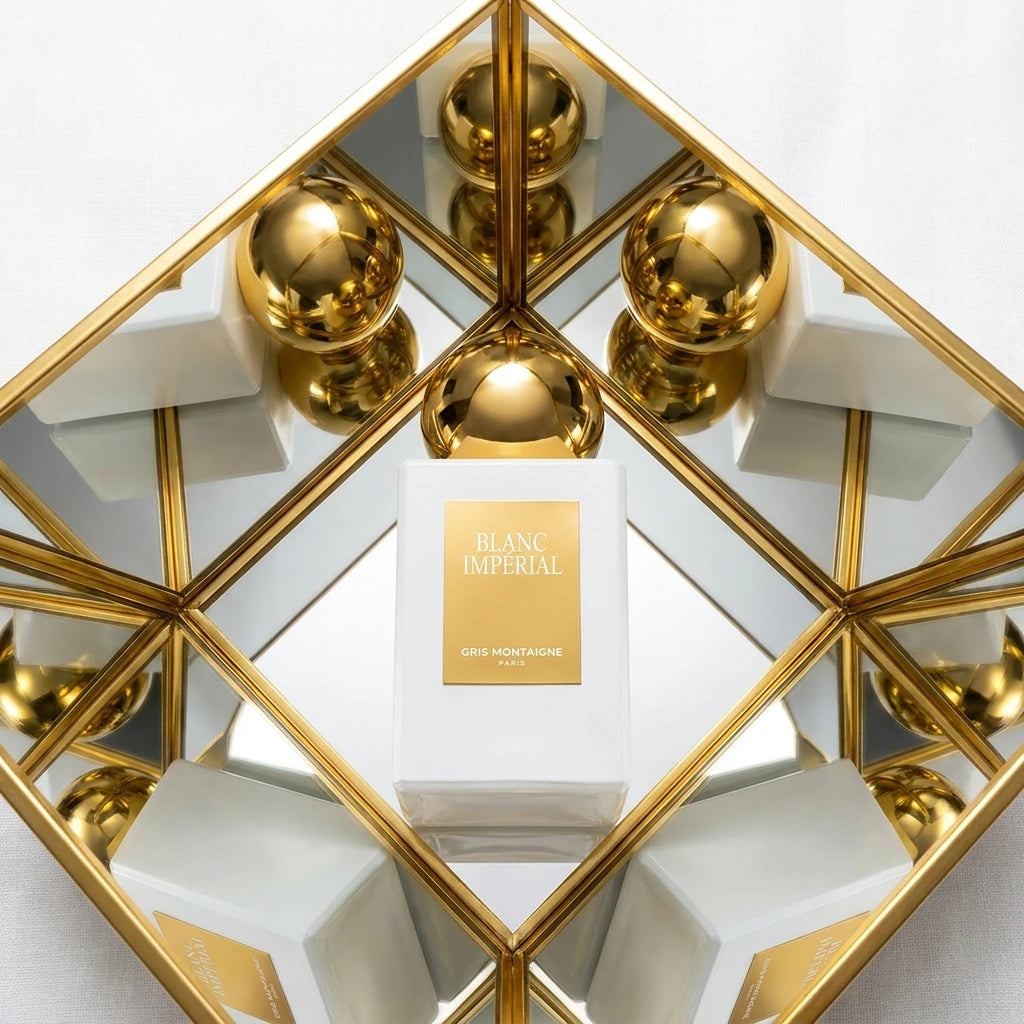 Un plan moyen en plongée à 60 degrés du flacon de image_7.png placé au centre d'une structure géométrique de miroirs dorés inclinés. Les miroirs reflètent à l'infini le capuchon doré et sphérique du flacon, créant un effet de couronne lumineuse. Le fond est une texture de lin blanc immaculé. Style : Composition artistique moderniste de studio. (gemini-3-pro-image-preview)
