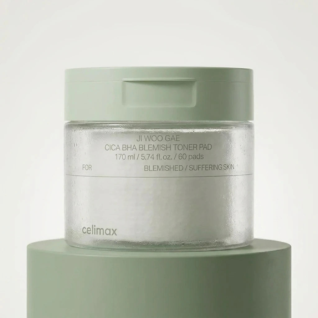 Commercial product photography of Celimax Ji Woo Gae Cica BHA Blemish Toner Pad jar, placed on a matte sage green pedestal. Clean minimalist background, soft professional studio lighting, crisp details, hyper-realistic texture, no CGI. Shot on 70mm lens, F7, ISO 250, photorealistic --ar 1:1 (gemini-3-pro-image-preview)