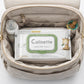 Lifestyle 1:1 product photograph of an open, modern canvas diaper bag, shot from directly above. The "Calinette - Lingettes Bébé Sensitive" pack is neatly placed in the main compartment, centered. Next to it, a small glass baby bottle and a colorful pacifier are subtly visible in side pockets, balanced within the square frame. Bright and clear natural lighting. Shot with a 70mm lens, f/4.0, ISO 250, highly realistic, tangible materials. --ar 1:1 (gpt-image-1.5)